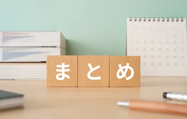 机の上に「まとめ」と書かれた3つの木製ブロックが並び、後ろに本とカレンダーが置かれている。